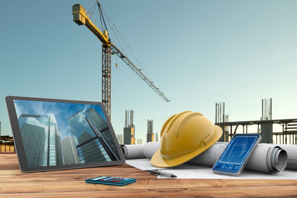 blueprints, safety helmet and computer in construction site